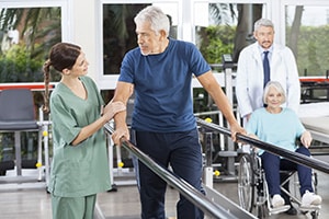 A rehab therapist with an elderly man in the rehab gym