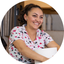 smiling housekeeper holding cleaning supplies